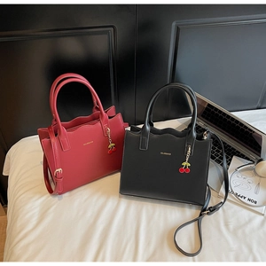 Detail of red and black leather tote bags with cherry charms and wavy edge design