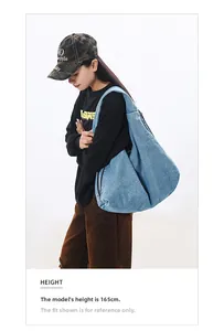 Detailed view of a light blue denim hobo bag worn by a 165cm model against a white background