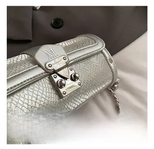 Close-up of silver snake pattern cylinder bag with metallic 'M' hardware lock