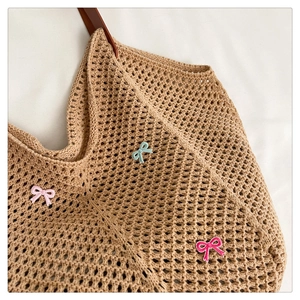 Detailed macro of khaki woven tote bag with colorful bows and leather handles