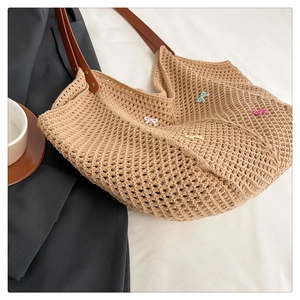 Detail of woven mesh crochet tote bag with mini pastel bows and leather shoulder strap