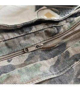 Close-up of durable metal zipper hardware on large camouflage canvas tote bag