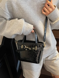 Mini black wrinkled patent leather tote bag with gold hardware shown on a model