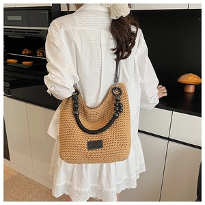 Detail of woven straw bucket bag featuring unique black beads and wooden handle design