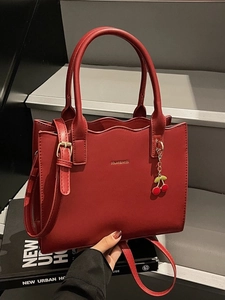Elegant red tote bag with scalloped edges, golden logo and cherry pendant accessory