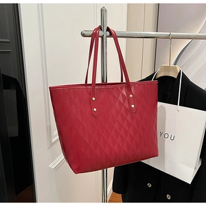 Detail of red quilted faux leather tote bag with geometric pattern and metal rivets