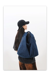 Detail of blue denim shoulder bag showing spacious capacity and vintage washed texture