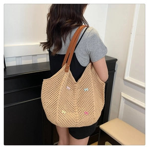 Detail of hollow woven tote bag featuring colorful bows and brown leather shoulder straps