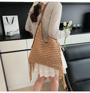 Detail of hand-woven crochet tote bag featuring long earth-tone tassels and leather strap
