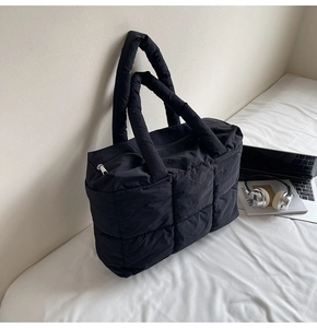 Detail of black quilted tote bag with padded handles and diamond pattern texture