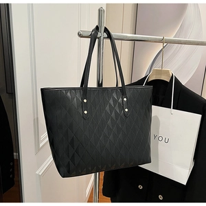 Detail of black quilted tote bag with silver rivets and smooth matte leather texture
