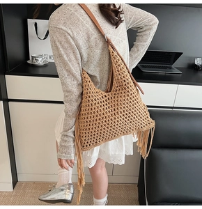 Detail of bohemian crochet hobo bag with tassel accents and brown leather shoulder strap