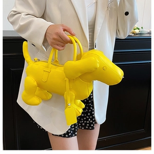 Detailansicht einer gelben Dackel-Handtasche, präsentiert von einem Model in Weiß