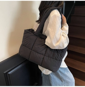 Close-up of black quilted puffer tote bag featuring square stitching and soft texture