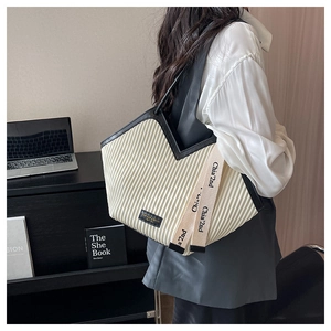 Détail d'un sac cabas plissé avec garniture noire en V et sangle décorative sur un modèle