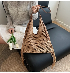 Detail of bohemian knit crochet hobo bag with long fringes and brown leather strap