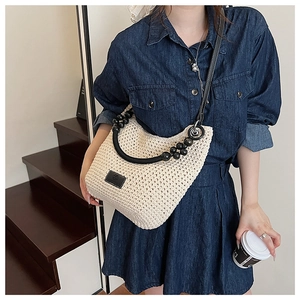 Detail of woven bucket bag with black round handle and decorative large beads