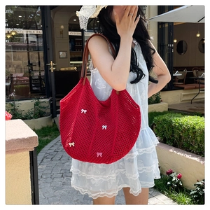 Close-up of a red hollow knit tote bag with colorful 3D bow charms and leather straps