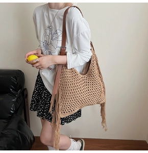 Close-up of bohemian woven tote bag featuring long fringes and brown leather strap