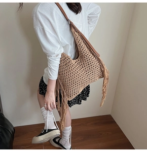Close-up of woven hobo tote bag with fringe details and adjustable brown strap