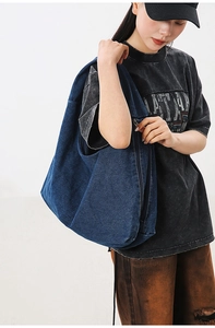 Detail view of large denim shoulder bag with zipper closure and washed twill texture