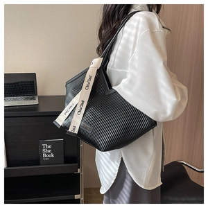 Détail du sac cabas plissé noir avec texture verticale et ruban décoratif blanc de marque