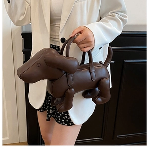 Dunkelbraune Handtasche in Dackelform aus Leder am Model in minimalistischem Raum