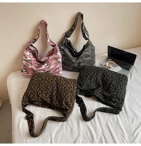 Flat lay of canvas messenger bags in leopard and camouflage prints with wide straps