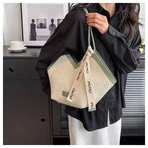 Détail du sac cabas plissé crème avec lanières vertes contrastées et ruban décoratif