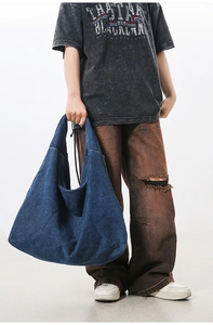 Close-up of a large washed denim tote bag showing distressed texture and spacious design