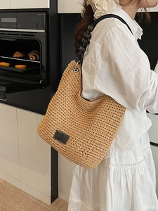 Modern woven bucket bag with large black beads handle and leather logo on front