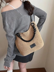 Woven bucket shoulder bag with black beaded handle and leather logo patch detail