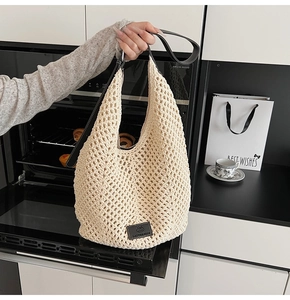 Détail du sac tressé ajouré avec bandoulière en cuir noir et écusson logo brodé