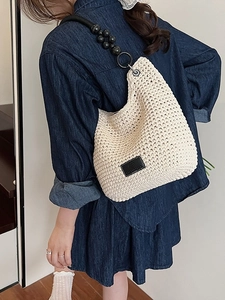 Chic beige woven bucket bag with black beaded strap and leather logo patch for women