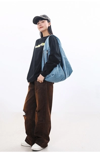 Detail of blue denim hobo bag featuring functional front zipper pockets for storage