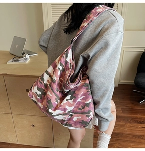 Detail of large pink camo canvas hobo bag with adjustable strap worn as a crossbody