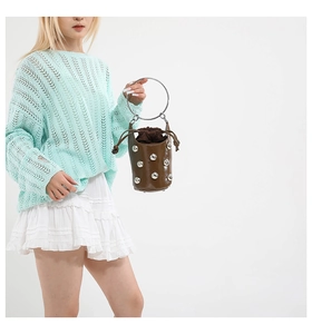 Détail du sac seau marron avec clous argentés et poignée en métal sur le mannequin