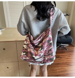 Detailed back view of a large purple camouflage canvas tote bag worn by a model