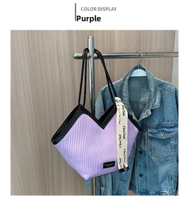 Détail du sac cabas plissé violet avec poignée noire et ruban décoratif en scène