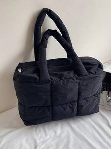 Large black quilted puffer tote bag with padded handles and zip closure for women