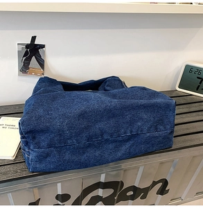Detail of deep blue denim tote bag with washed texture and sturdy stitching on a counter