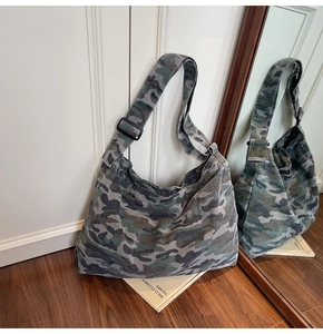 Detail of camouflage canvas hobo bag with adjustable strap on wooden floor