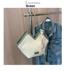 Vue détaillée du sac cabas plissé vert avec ruban de lettres suspendu sur un cintre