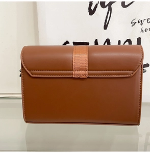 Detail of caramel brown leather box bag with vertical textured strap and neat stitching