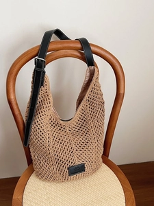 Sac fourre-tout chic en paille tressée ajourée avec bandoulière en cuir noir sur chaise