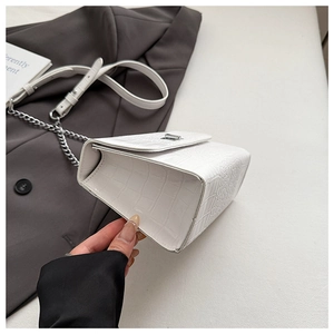 Detail of white crocodile embossed leather flap bag with silver chain and magnetic closure