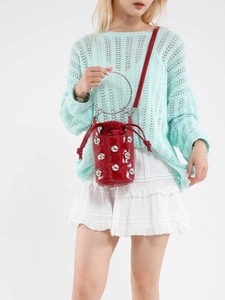 Sac seau en cuir verni rouge avec clous et anse anneau en métal sur modèle