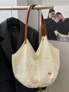 Cream crochet tote bag with colorful bows and brown leather handles on a hanger