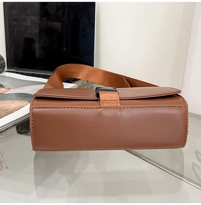 Detail view of the brown leather messenger bag featuring wide strap and buckle closure