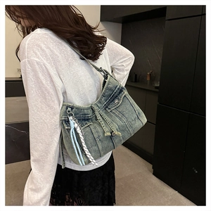 Détail d'un sac cabas en jean vintage montrant le tissu délavé et les poches décoratives
